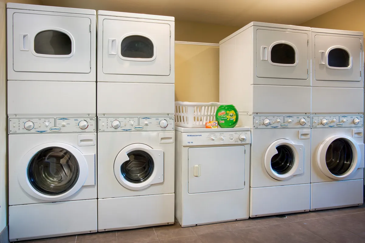 A convenient in-house laundry area featuring a stacked washer and dryer beside a laundry basket. The space is clean and practical, emphasizing one of the key amenities that make family travel stress-free.