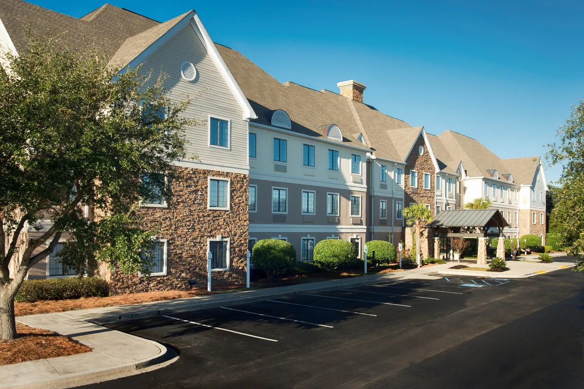 The main entrance of the hotel with a landscaped area and large windows letting in natural light. The inviting scene suggests a welcoming atmosphere, perfect for arrivals and departures as families come and go on their local adventures.