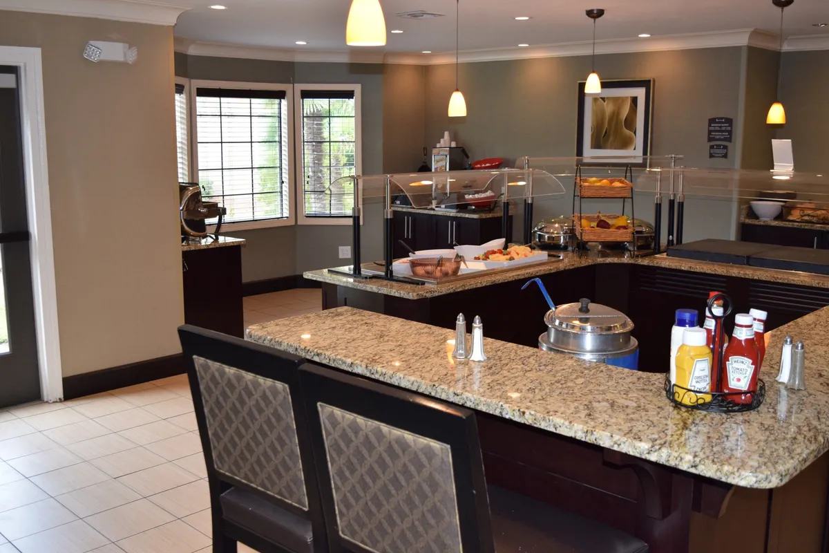 A close-up of a granite countertop displaying a tempting breakfast spread and a condiment station, inviting guests to assemble their own perfect meal. The scene feels approachable and homey, highlighting the self-serve aspect.