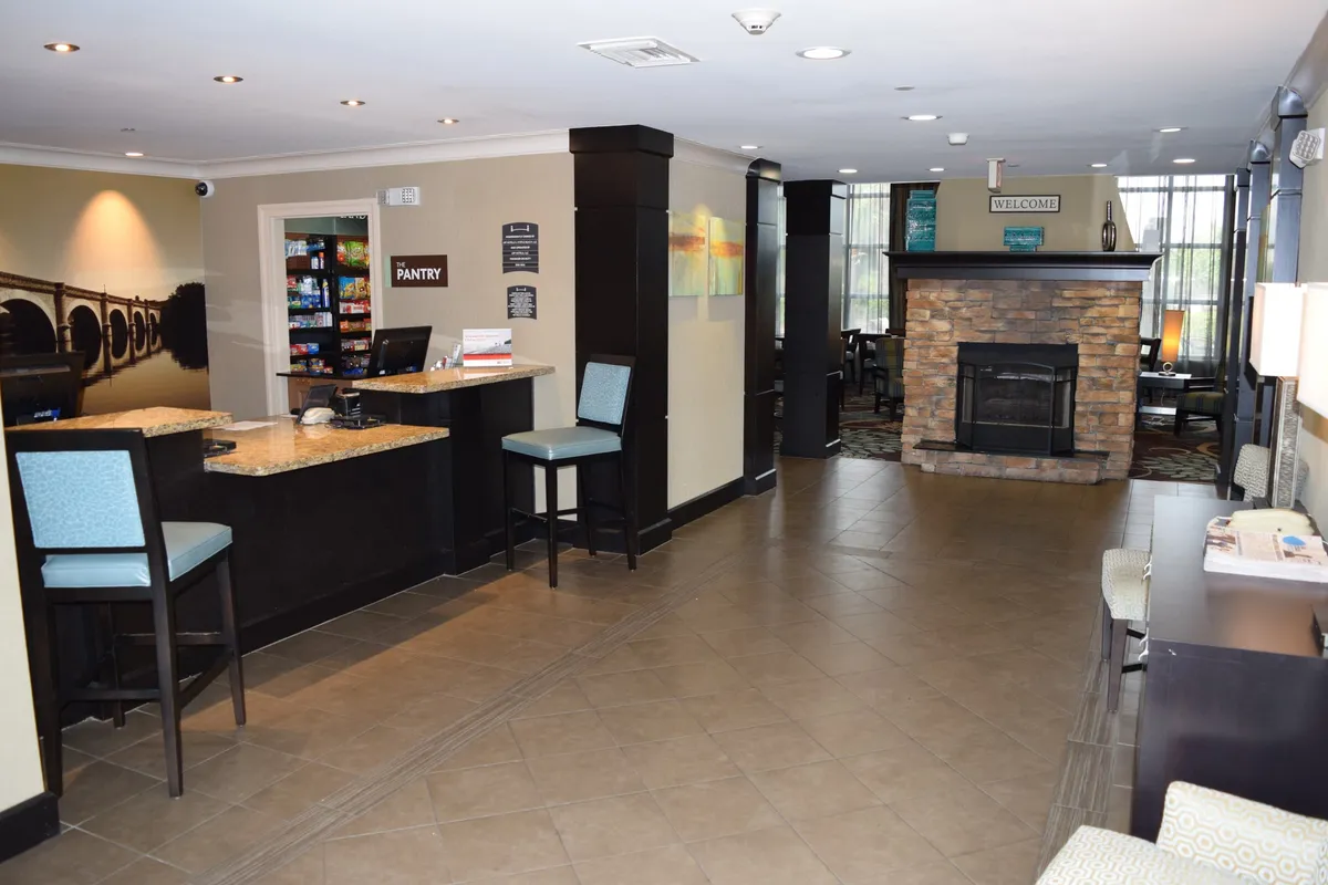 A bright, inviting reception area with a cozy seating arrangement, a pantry area, fireplace, and a welcoming atmosphere. Guests can relax by the fire or connect in the communal space, reinforcing the idea of comfort and connection.