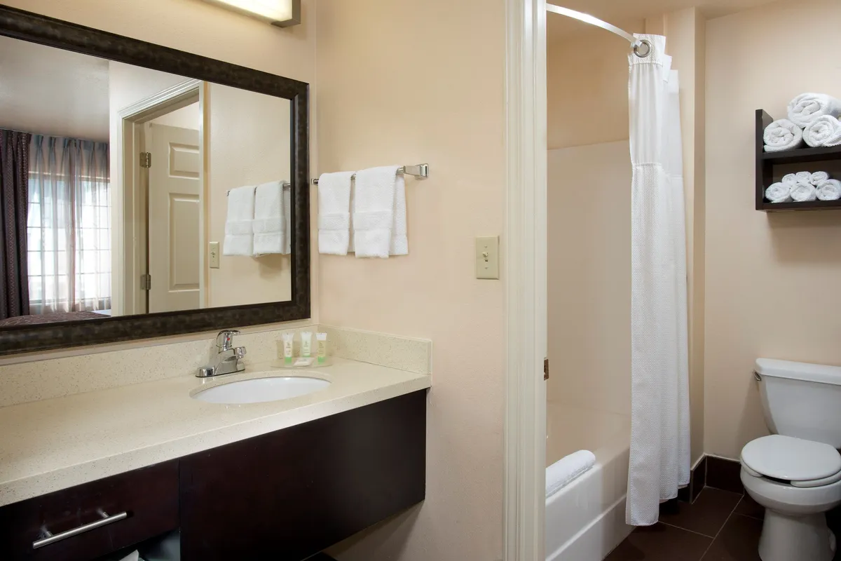 A modern bathroom with a spacious countertop, mirror, neatly stacked fresh towels, a walk-in shower area, and toilet. The overall ambiance is clean, refreshing, and spa-like—ideal for unwinding or preparing for the day.