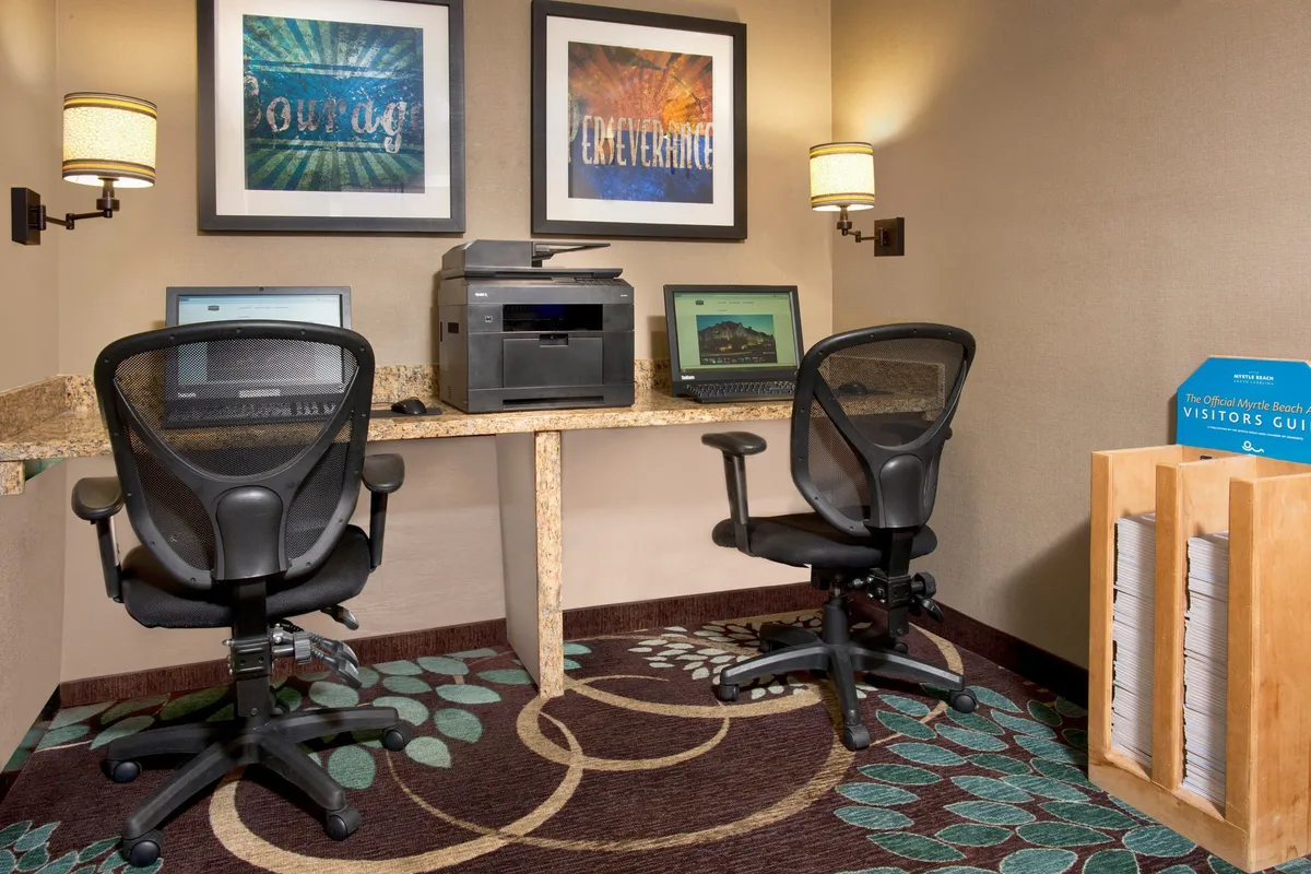 A welcoming business center interior with workstations, computers, and visitor guides. The space feels productive and guest-friendly, emphasizing convenience for business travelers and planners.